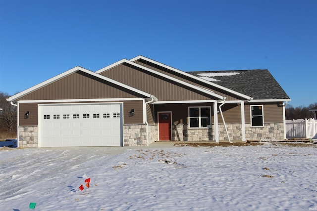 craftsman-style home featuring an attached garage, fence, covered porch, and stone siding