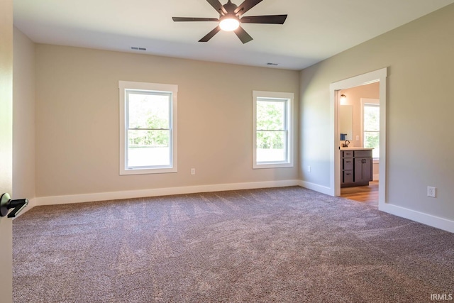 carpeted empty room with ceiling fan and a wealth of natural light