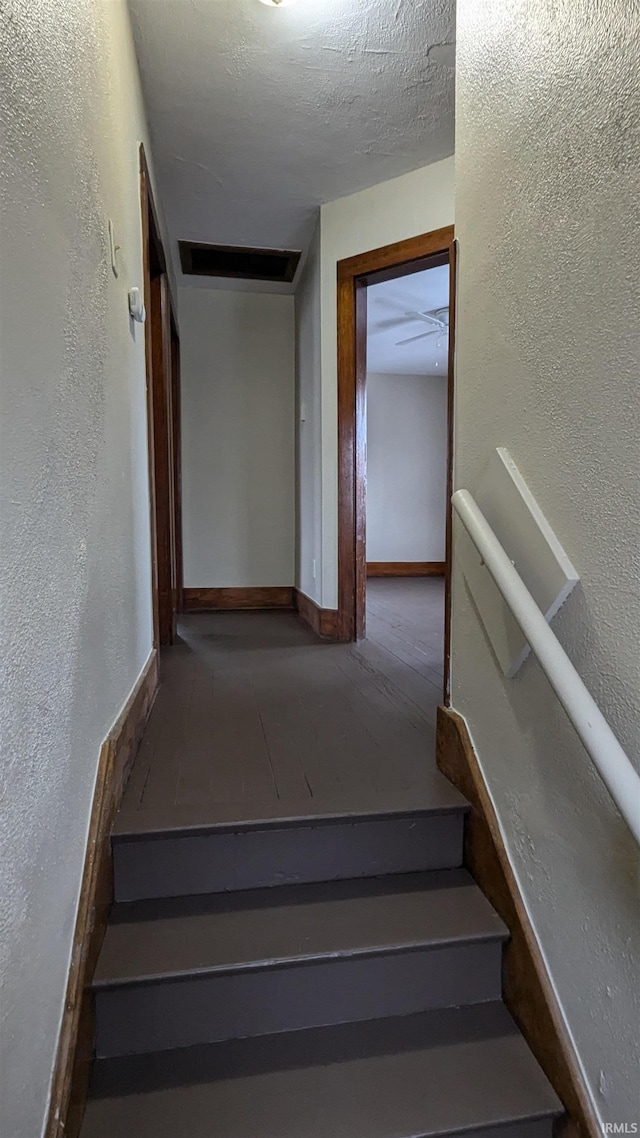 stairs featuring a textured ceiling