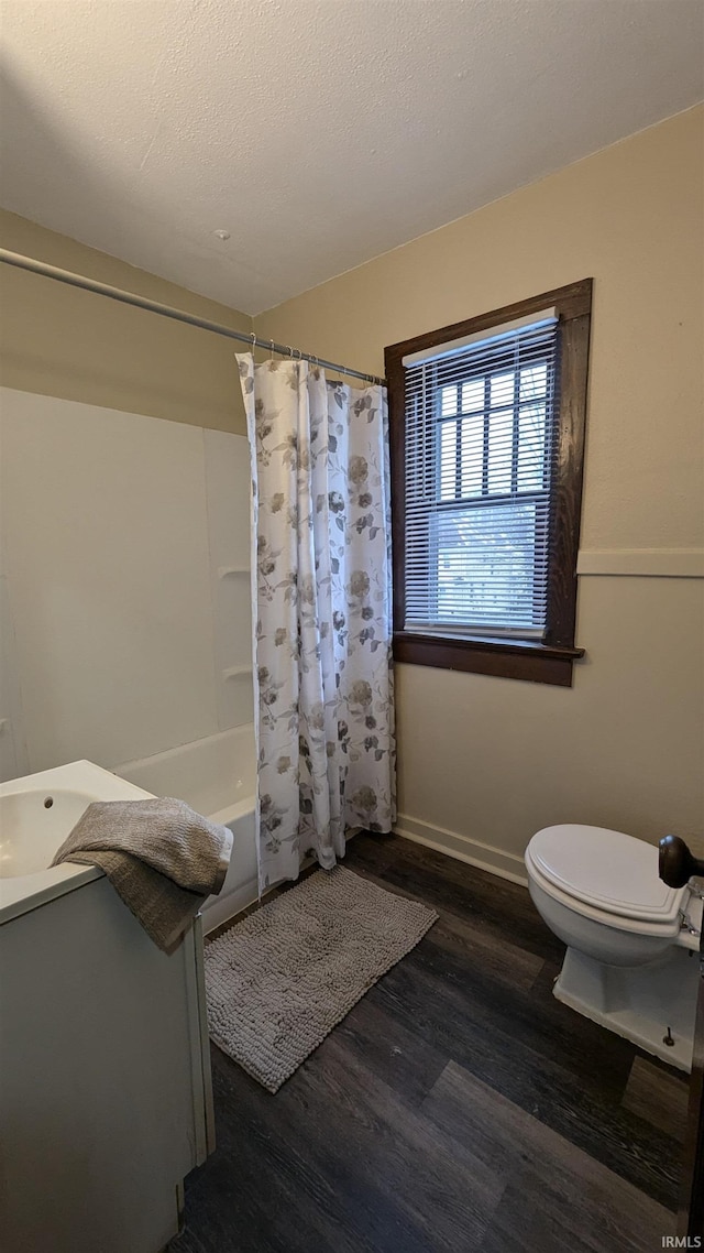 full bathroom with toilet, shower / tub combo, hardwood / wood-style floors, a textured ceiling, and vanity