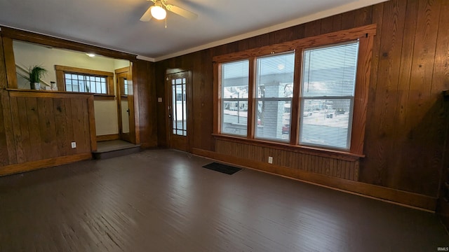 interior space featuring wood walls, ceiling fan, and dark hardwood / wood-style flooring