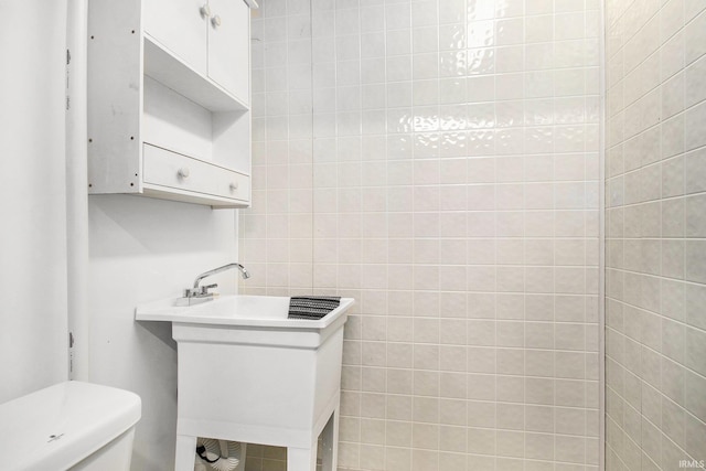 bathroom with sink, tile walls, and toilet