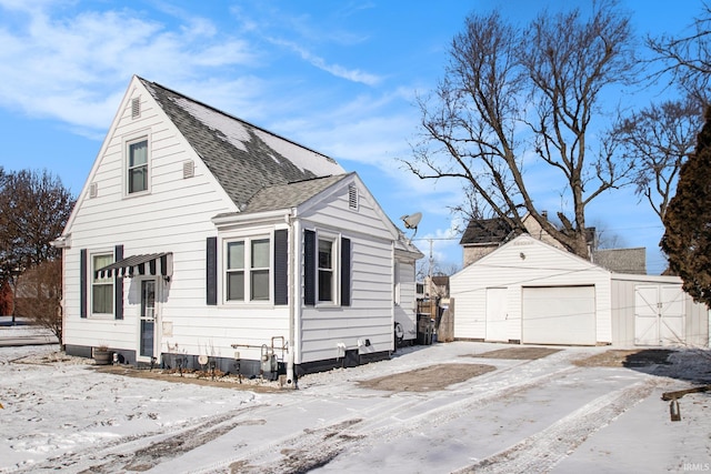 snow covered property featuring an outdoor structure and a garage