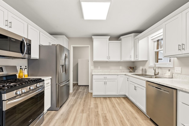 kitchen featuring sink, white cabinetry, light stone counters, and appliances with stainless steel finishes