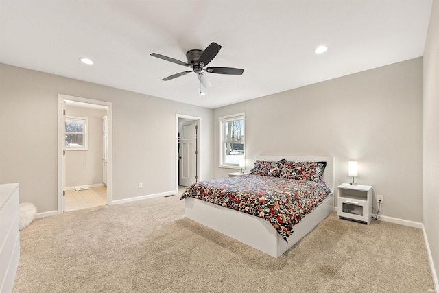 bedroom with ceiling fan, light colored carpet, and ensuite bath