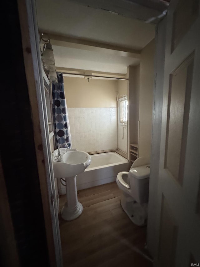 bathroom with hardwood / wood-style floors, toilet, and shower / tub combo with curtain