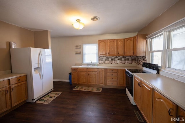 kitchen featuring sink, white appliances, dark hardwood / wood-style floors, and a healthy amount of sunlight