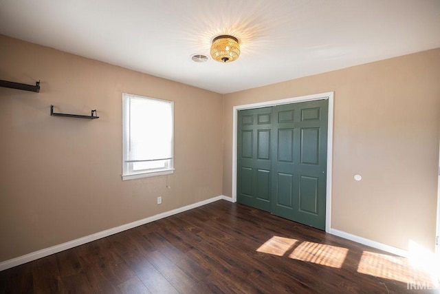 unfurnished bedroom featuring a closet and dark hardwood / wood-style flooring