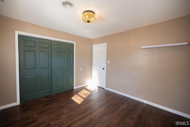 unfurnished bedroom featuring dark hardwood / wood-style floors and a closet