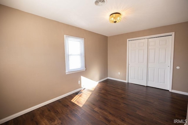 unfurnished bedroom with dark hardwood / wood-style floors and a closet