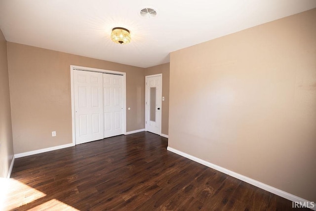 unfurnished bedroom with dark hardwood / wood-style floors and a closet