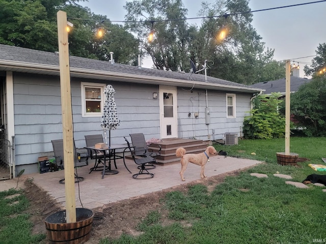 rear view of house featuring cooling unit, a patio area, and a lawn