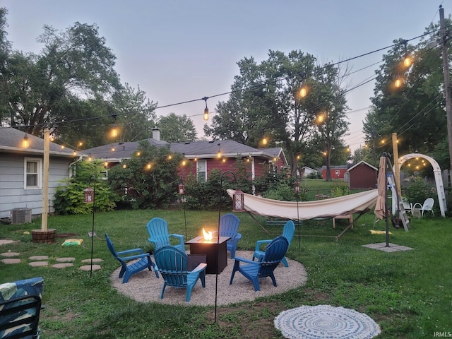 yard at dusk featuring cooling unit and an outdoor fire pit