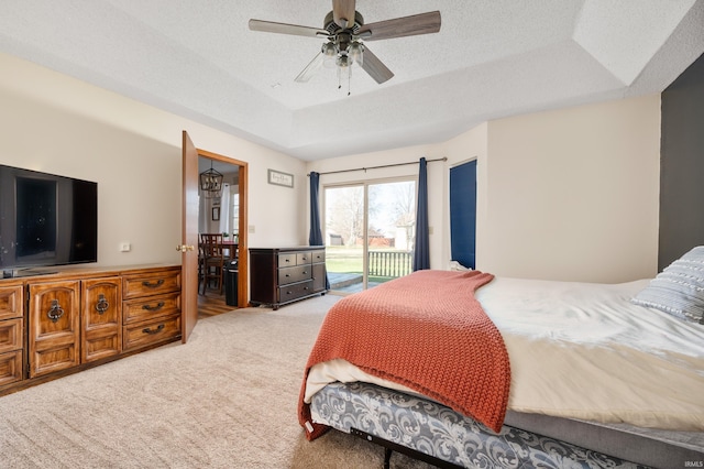 bedroom with a raised ceiling, light carpet, access to exterior, and ceiling fan