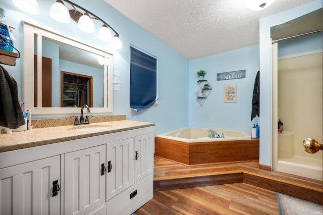 bathroom featuring hardwood / wood-style flooring, vanity, shower with separate bathtub, and a textured ceiling