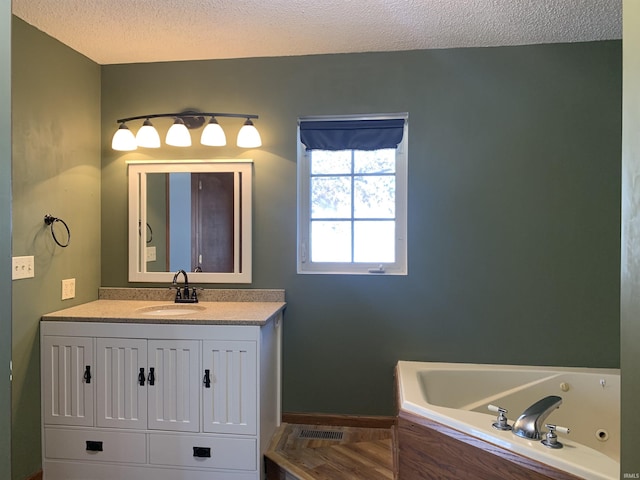 bathroom featuring vanity, a textured ceiling, and a tub