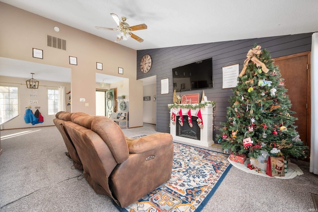 living room featuring vaulted ceiling, wood walls, ceiling fan, and carpet flooring