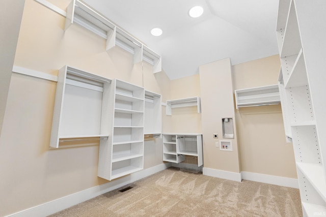 walk in closet with light colored carpet