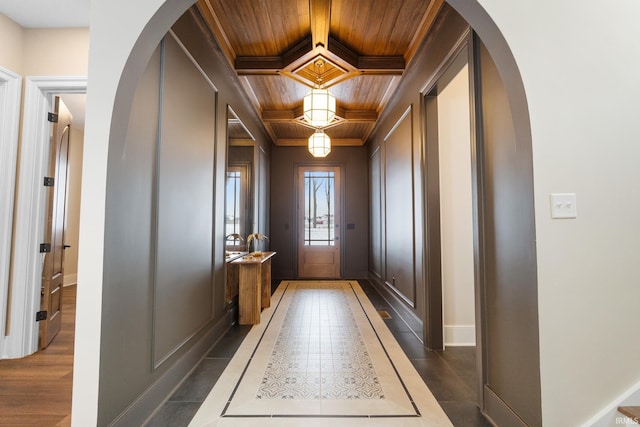 doorway featuring wood ceiling, coffered ceiling, beam ceiling, and ornamental molding