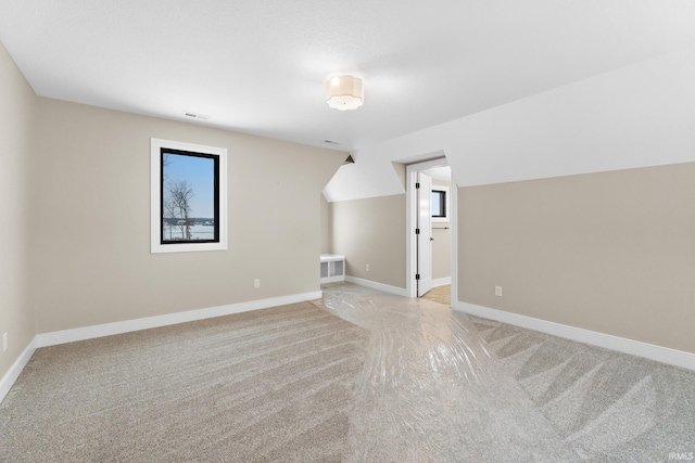 additional living space with lofted ceiling and light carpet