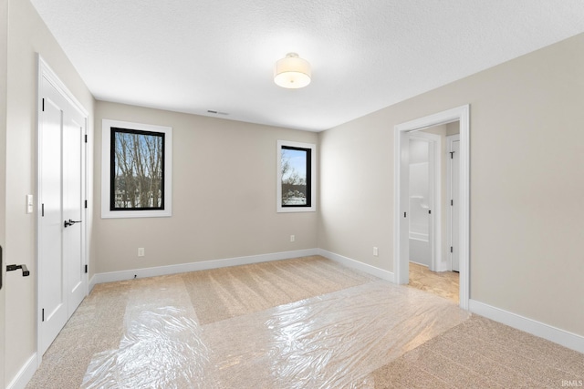 empty room with a textured ceiling and light colored carpet