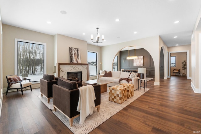 living room with plenty of natural light, dark wood-type flooring, and a notable chandelier