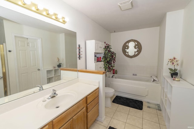 bathroom with a tub, toilet, vanity, and tile patterned flooring