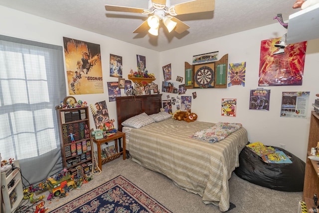 carpeted bedroom with ceiling fan and a textured ceiling