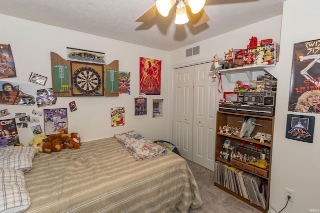 carpeted bedroom featuring a closet, ceiling fan, and a textured ceiling