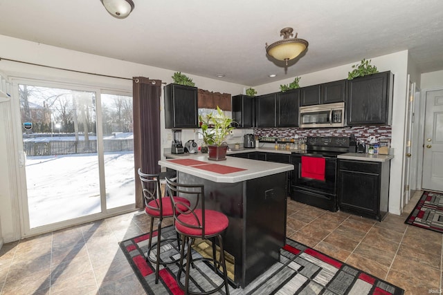 kitchen with black range with electric stovetop, a kitchen island, a breakfast bar area, and tasteful backsplash