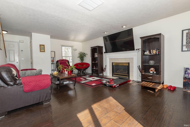 living room featuring a textured ceiling, dark wood-type flooring, and a fireplace