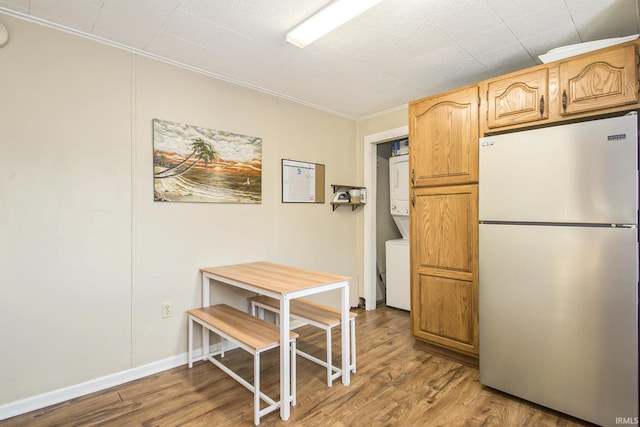 kitchen featuring stacked washer / dryer, stainless steel fridge, and hardwood / wood-style floors