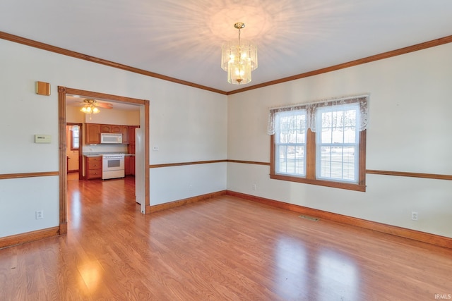 spare room with an inviting chandelier, light wood-type flooring, and ornamental molding