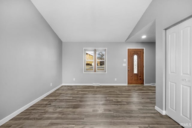 foyer entrance with dark wood-type flooring and vaulted ceiling