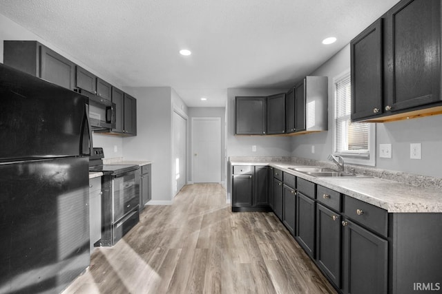 kitchen with black appliances, light hardwood / wood-style floors, a textured ceiling, and sink