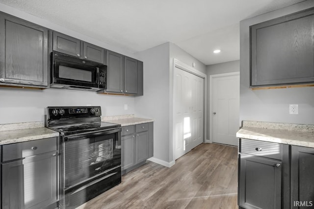 kitchen featuring gray cabinets, black appliances, and light hardwood / wood-style flooring