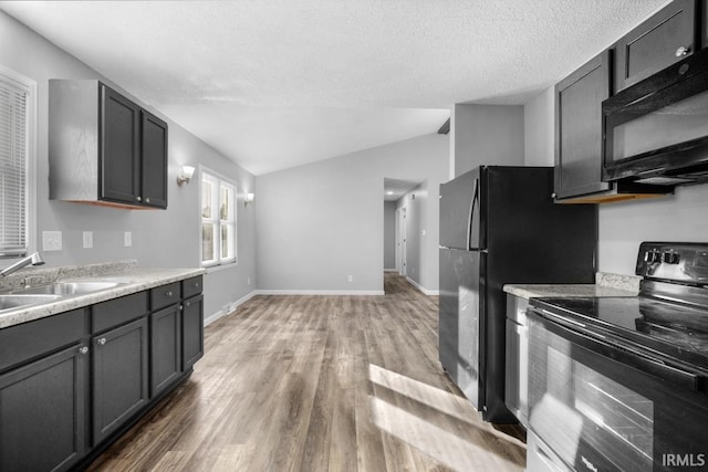 kitchen with sink, hardwood / wood-style flooring, a textured ceiling, black appliances, and lofted ceiling