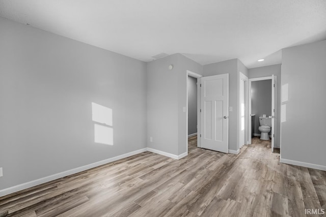 unfurnished bedroom with light hardwood / wood-style flooring and ensuite bath