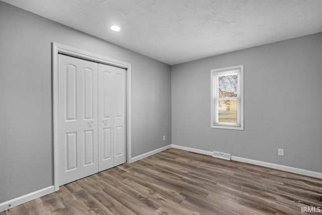 unfurnished bedroom featuring a closet and hardwood / wood-style flooring