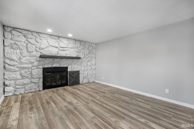 unfurnished living room featuring hardwood / wood-style flooring, a textured ceiling, and a fireplace