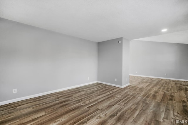 empty room with dark wood-type flooring and vaulted ceiling