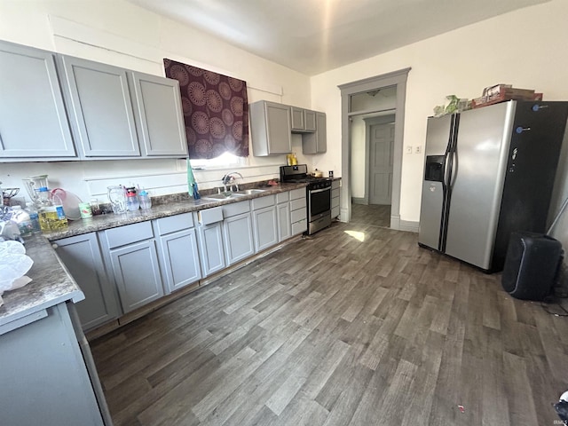 kitchen featuring sink, light stone countertops, gray cabinets, dark hardwood / wood-style floors, and stainless steel appliances