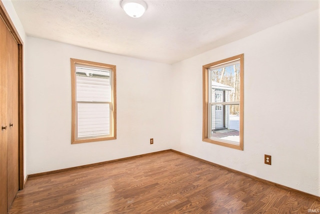 unfurnished room featuring dark wood-type flooring and a textured ceiling