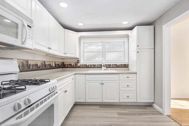 kitchen featuring white cabinetry, sink, white appliances, and light wood-type flooring