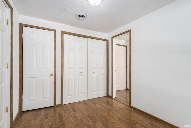 unfurnished bedroom featuring dark wood-type flooring and a textured ceiling