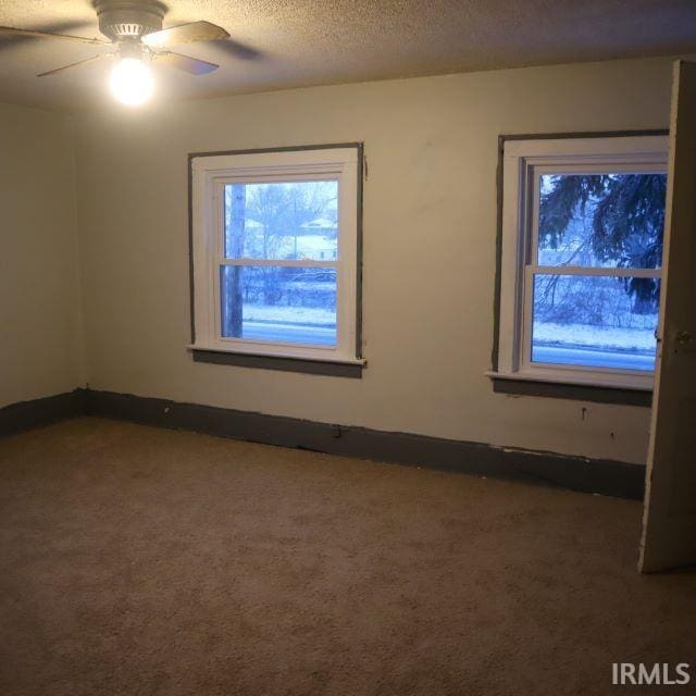 empty room with ceiling fan, a textured ceiling, and carpet floors