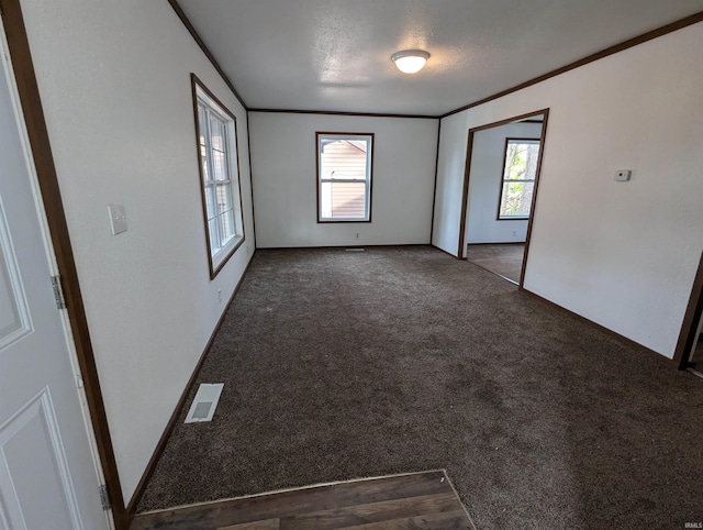 spare room with ornamental molding, dark colored carpet, and a textured ceiling