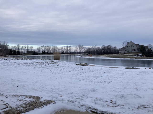 yard covered in snow featuring a detached garage and a water view