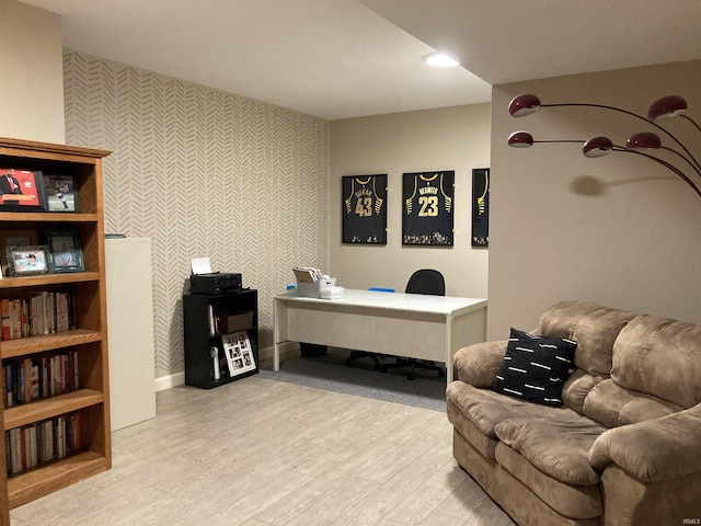 office area with light wood-style flooring, an accent wall, and baseboards