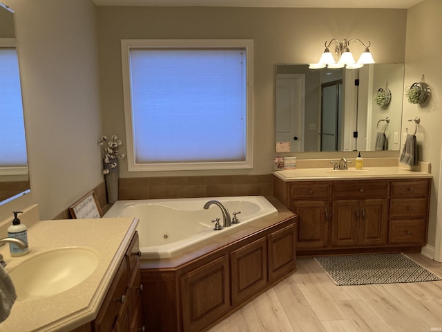 bathroom with a whirlpool tub, wood finished floors, two vanities, and a sink